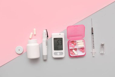 Renk arkaplanı üzerinde neşter, insülin ampülü, şırınga ve haplarla modern glukometre