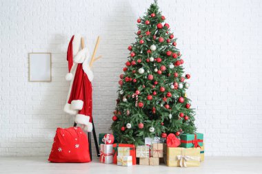 İçinde Noel Baba kostümü, Noel ağacı ve hediyeler olan bir oda.