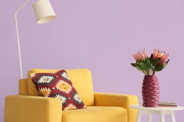 Oturma odasında üzerinde protea çiçekleri ve dergiler olan bir vazo.