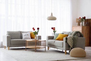 Gri kanepeleri ve kahve masasında güzel çiçekleri olan şık bir oturma odası.