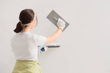 Sırtında oyuncak bıçaklar olan genç bir kadın ışık duvarının yanında çalışıyor.