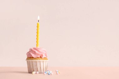 Tatlı doğum günü keki yanan mum ve bej arka planda serpiştirilmiş