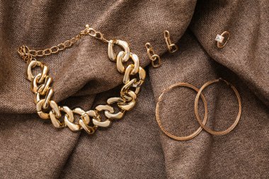 Kumaş arka planda farklı altın mücevherler.