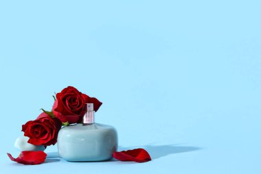 Mavi arka planda güzel kırmızı güller olan bir şişe parfüm. Sevgililer Günü kutlaması