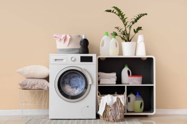 Çamaşır makinesi, raf ünitesi ve deterjanı olan bir çamaşırhane.