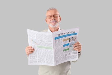 Gri arka planda gazetesi olan kıdemli işadamı.