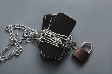 Koyu arkaplanda zincir ve asma kilit olan farklı cep telefonları