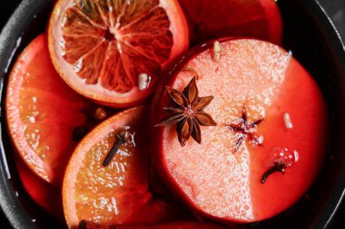 Siyah arka planda elma ve portakallı sıcak şarap tenceresi, yakın plan.