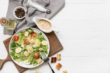Lezzetli Sezar salatası, karabiber ve ahşap arka planda sos teknesi.