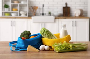 Mutfaktaki ahşap masada farklı taze ürünlerin olduğu alışveriş torbaları.