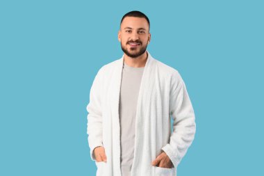 Mavi arka planda gülümseyen genç adam.