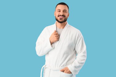 Mavi arka planda gülümseyen genç adam.