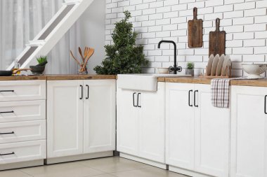 Mutfak tezgahlarındaki aletler beyaz tuğla duvarın yanında.