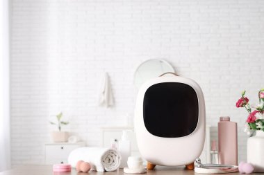 Cilt ürünleri, havlu ve vazodaki çiçeklerle kaplı kapalı kozmetik buzdolabı beyaz duvarın yanındaki masada. Yakın çekim.