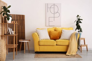 Sarı kanepeli, çiçekli ve masalı aydınlık oturma odasının içi.