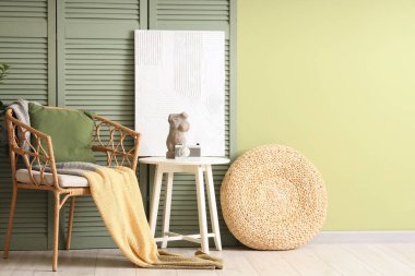 Oturma odasının içinde yeşil katlı ekran, koltuk ve masa.