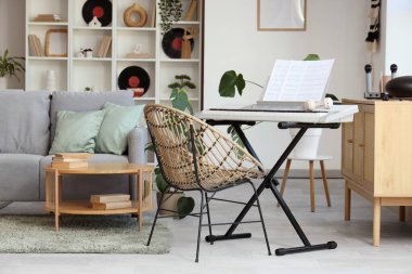 Oturma odasının içinde kanepe, sentezleyici ve vinil diskler var.