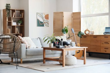 Oturma odasının içinde kanepe, masa ve müzik aletleri var.