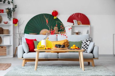 Çin Yeni Yıl kutlamaları için kanepe, masa ve dekorla aydınlık oturma odasının içinde.