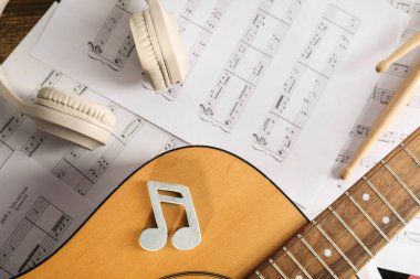 Müzik kağıtları, gitar ve modern kulaklıklar, yakın çekim.