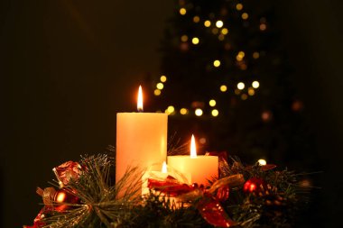 Akşamları yanan mumlar ve Noel çelengi ile süslenmiş köknar ağacına karşı kompozisyon