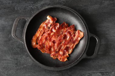 Siyah arka planda kızarmış pastırma pastırmalı kızartma tavası.