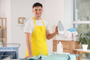 Evde demir ve gömleği olan yakışıklı genç adam.