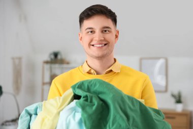 Evde bir yığın temiz giysisi olan yakışıklı genç adam.
