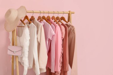 Odada pembe duvarın yanında giysi, şapka ve çanta var.