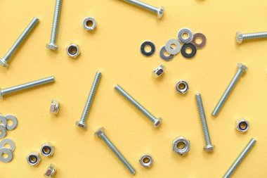 Sarı arka planda musluk cıvataları, çamaşır makineleri ve krom fındıklar