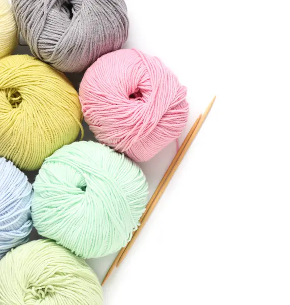 Beyaz arka planda iğneli renkli örgü ipliği