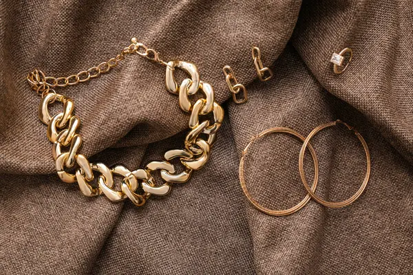 Kumaş arka planda farklı altın mücevherler.