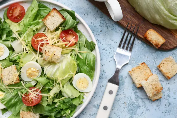 Mavi arka planda lezzetli Sezar salatası tabağı, yakın plan.