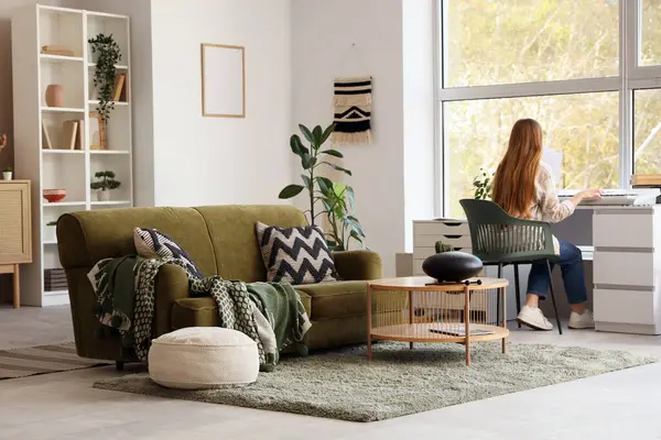 Oturma odasında, arka planda sentezleyici oynayan genç bir kadın.