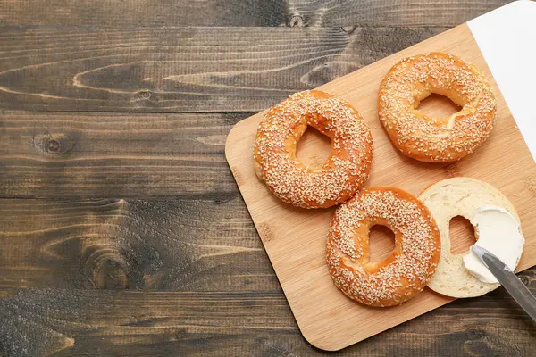 Tahta arka planda susam tohumlu lezzetli simit kesme tahtası