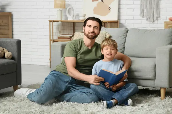 Babam ve küçük oğlu evde kitap okuyorlar. Babalar Günü.