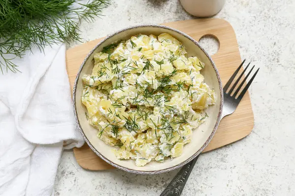 Bir kase lezzetli patates salatası, dereotlu, ekşi kremalı ve çatallı hafif grunge arkaplanlı.