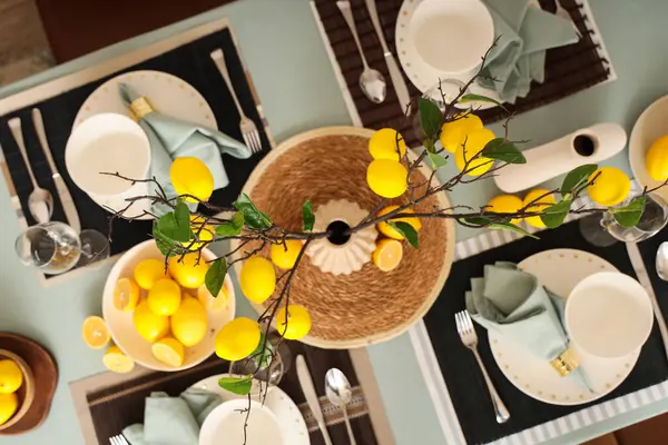 Masa düzeniyle dekore edilmiş şık masa dekorları, yemek odasında taze narenciye ve limon ağacı dalları, üst manzara.