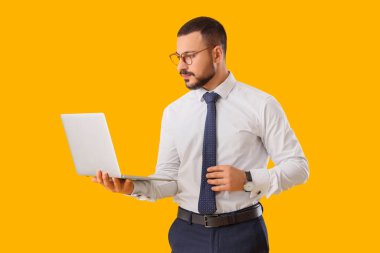 Sarı arka planda kravat ve dizüstü bilgisayarı olan genç bir iş adamı