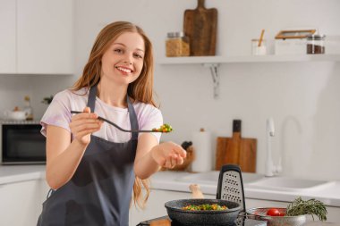 Mutfakta sebze kızartan genç bir kadın.