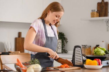 Mutfakta havuç kesen genç bir kadın.