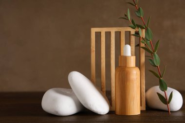 Kaliteli yağ şişesi, spa taşları ve okaliptüs dalı ile ahşap masa kompozisyonu
