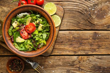 Çeri domatesli avokado salatası ve ahşap arka planda limon.