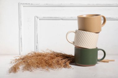 Açık arkaplanda kuru sazlıklar bulunan farklı seramik kupalar