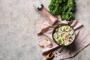 Yengeç saplı bir kase salata, buzdağı yaprakları, mısır, salatalık ve bıldırcın yumurtası gri grunge arka planda.