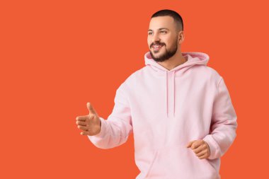 Turuncu arka planda el sıkışmak isteyen genç bir adam. Kural kavramı