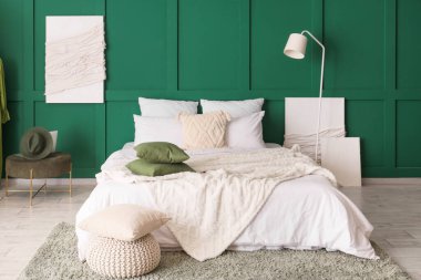 Yatak odasının içinde resimler, lambalar ve puflar var.