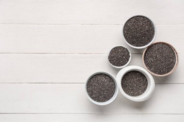 Beyaz ahşap arka planda chia tohumları olan kaseler