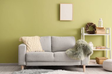 Oturma odasının içinde kanepe, boş çerçeve ve rafta Noel çelengi var.