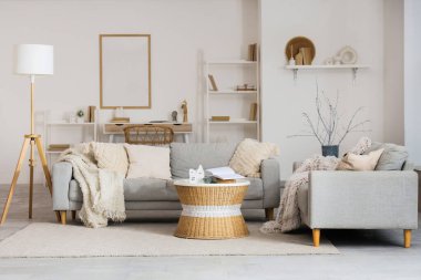 Masanın üzerinde gri kanepeler ve Noel dallarıyla aydınlık oturma odasının içinde.